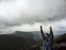 woman on a mountain top with raised hands 