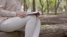 a woman reading a Bible in a park 