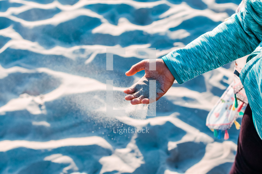 a child playing with sand on a beach 
