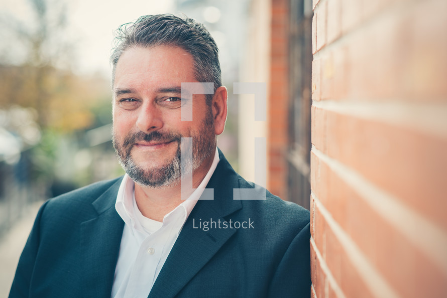 man leaning against a brick wall 