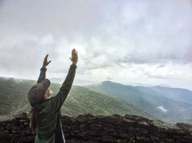 woman standing with raised arms on a mountain top 