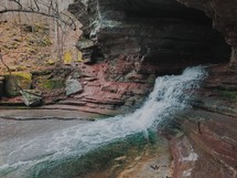 waterfall flowing from the mouth of a cave 