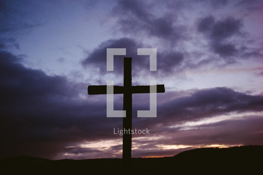 Silhouette of a wooden cross at nightfall.