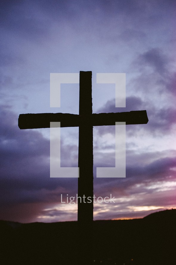 Silhouette of a wooden cross at nightfall.