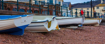 Small fishing boats lined up on a pebble beach in Sidmouth, England