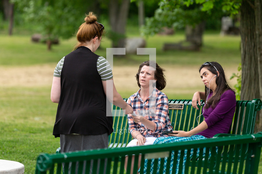 Woman handing gospel tract to people on park bench