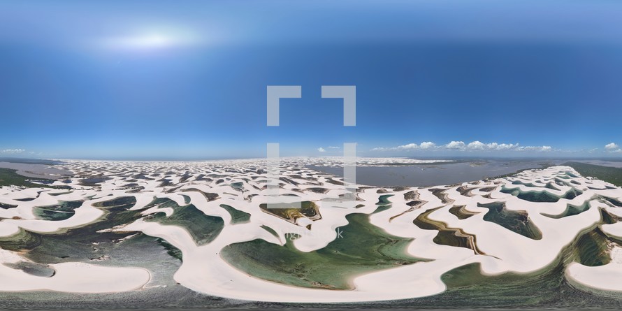 360 aerial photo taken with drone high above sand dunes of Lençóis Maranhenses meeting a river on northeast coast of Brazil