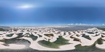 360 aerial photo taken with drone high above sand dunes of Lençóis Maranhenses meeting a river on northeast coast of Brazil