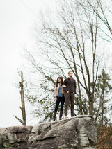 man and woman standing on the edge of a rock