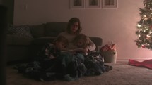 a mother reading to her children at Christmas 