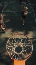 Young men playing basketball on an outdoor court on a sunny day