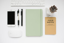 computer keyboard, field notes book, journal, pens, computer mouse, succulent plant, desk, white background
