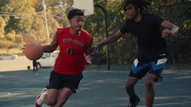 Young men playing basketball on an outdoor court on a sunny day