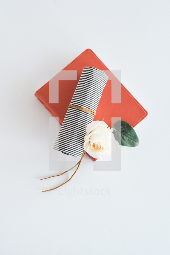 orange journal, cloth roll, and rose 