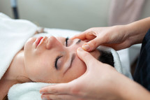 face of young woman having facial massage at spa.