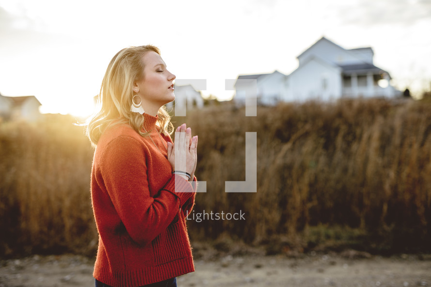 woman praying standing in the middle of train tracks 