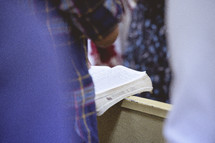 man standing reading a Bible during a worship service 