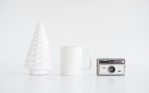 white tree figurine, coffee mug, camera 