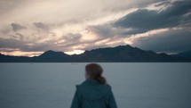 Young woman enjoying beautiful sunset and Mountain View in the Great Salt Flats