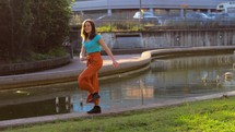 Woman marching and dancing near a fountain at a park.