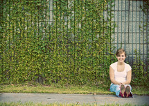 Woman sitting in front of ivy covered wall