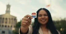 Young woman smiling with an ‘I Voted’ stickers and pin 