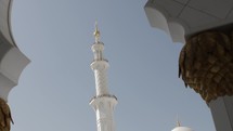 Mosque minaret tower in front of sunshine and clouds in Abu Dhabi. 