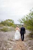 bride and groom walking down an outdoor trail