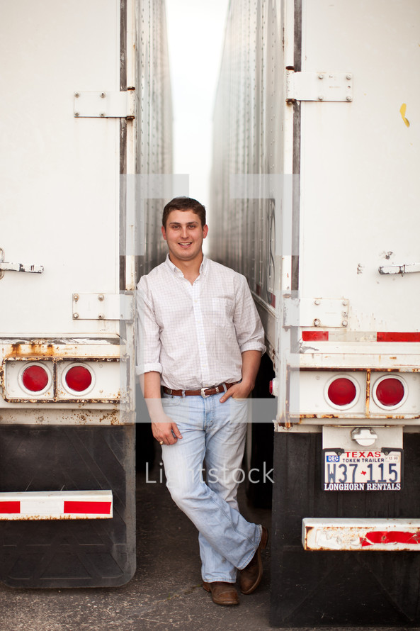 man standing between two tractor trailer trucks