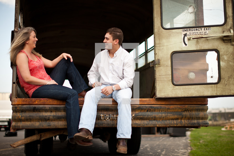 Happy couple sitting on back of abandoned bus