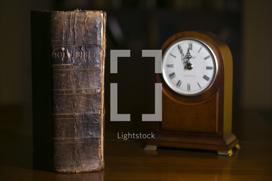 old leather Bible and clock on a table 