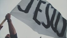 man waving a white flag with the word Jesus 