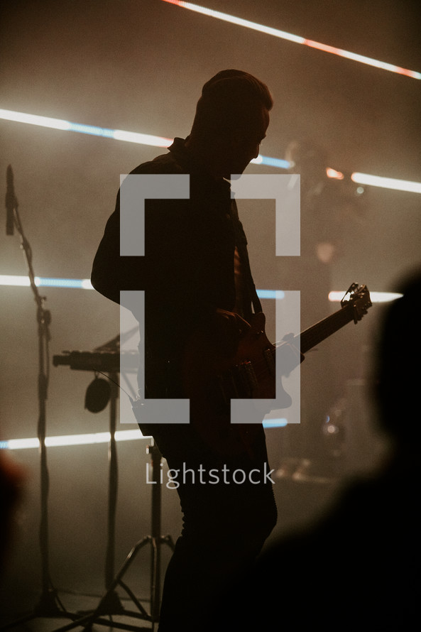 Man playing guitar silhouette in a worship setting