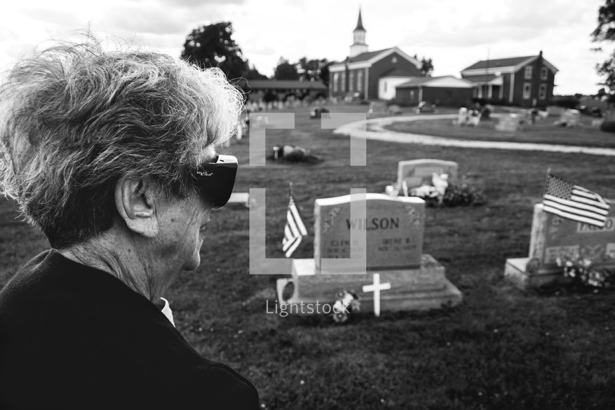 An elderly woman visiting a cemetery 