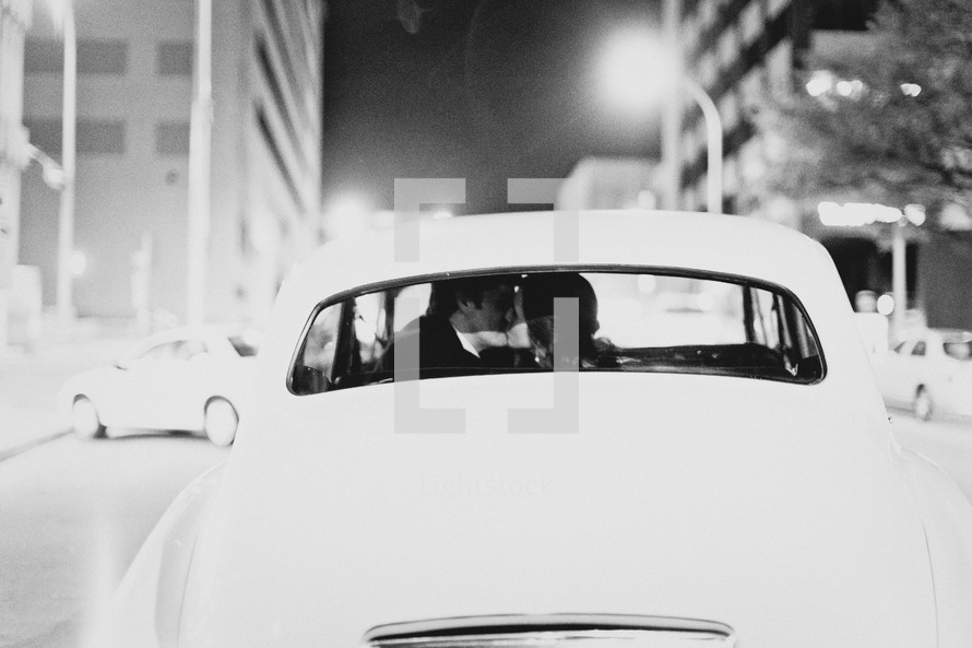 A married couple kissing as they drive away from their wedding