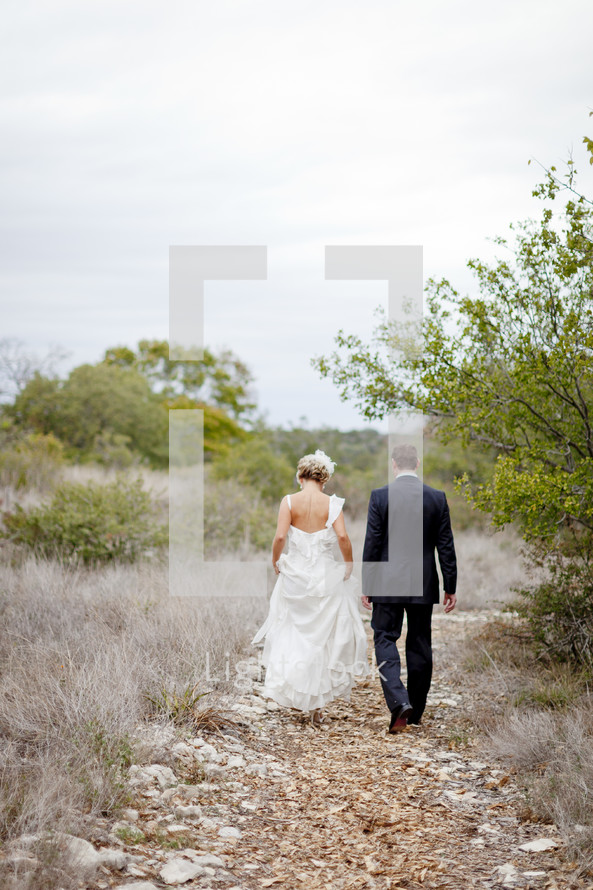 bride and groom walking down an outdoor trail