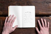 Hands on a wooden table with a scripture card.
