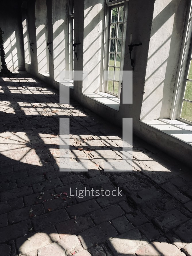 sunlight shining through windows onto a stone floor 