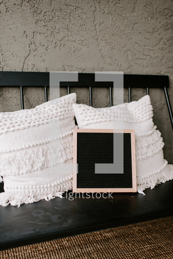 throw pillows on a bench and letter board 