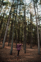 woman walking through a forest in a plaid shirt 