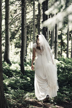 bride walking through a forest 