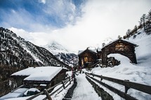 A small snow covered village with wooden cabins near Zermatt, Switzerland with the Matterhorn covered in clouds