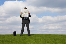 Businessman reading a map in a field 