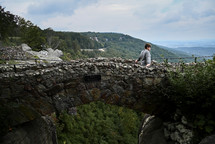 a man standing on a stone bridge 