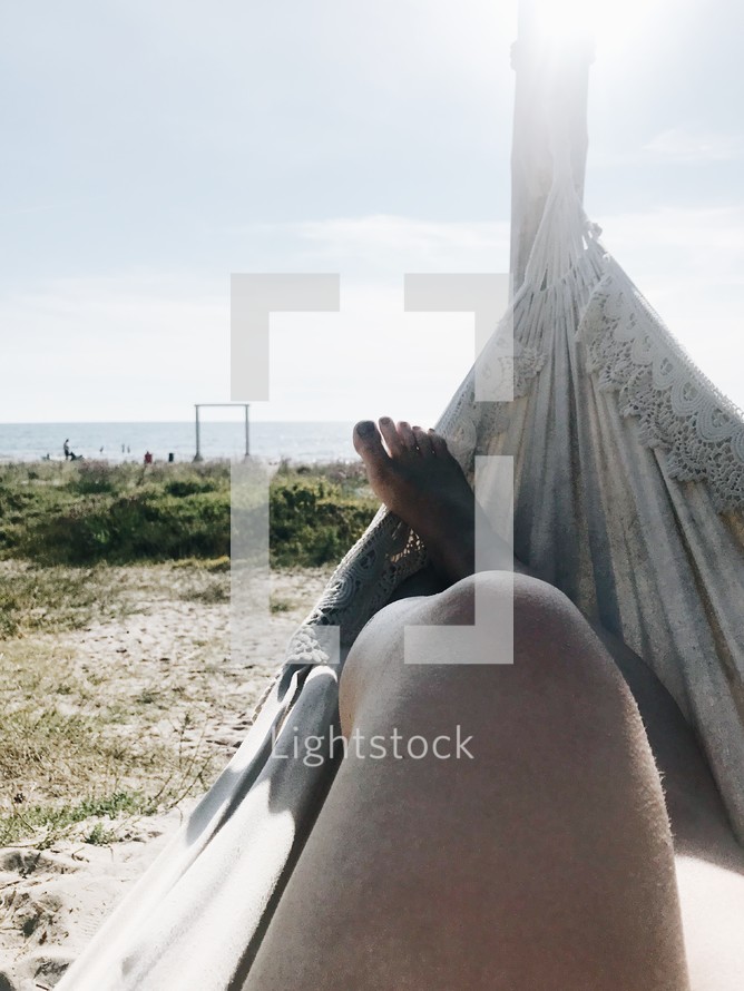 a woman sitting in a hammock on a beach 