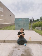 young man sitting on a curb 