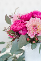 A bouquet of pink peonies in a white vase.