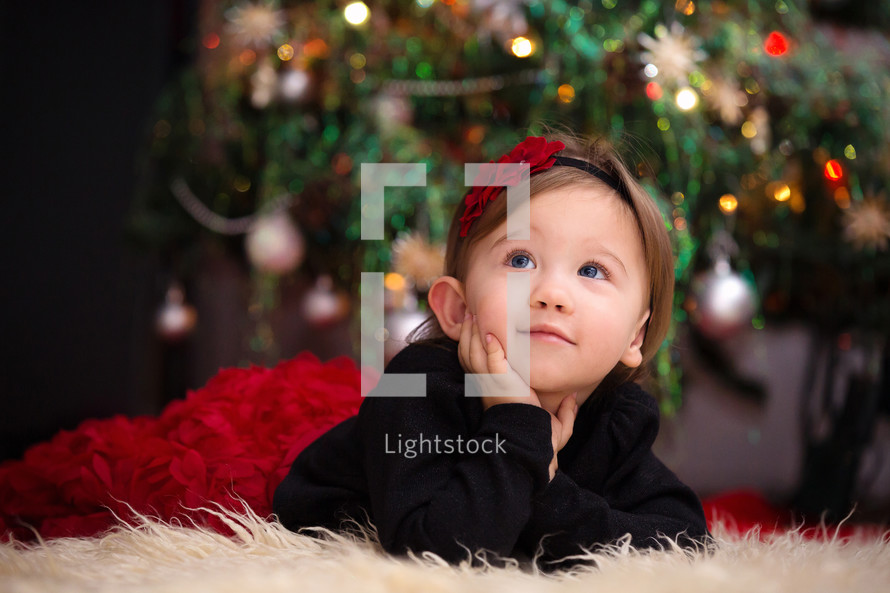 toddler girl on a fur rug under a Christmas tree