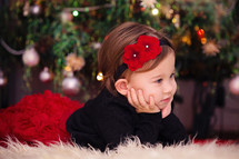 toddler girl on a fur rug under a Christmas tree 