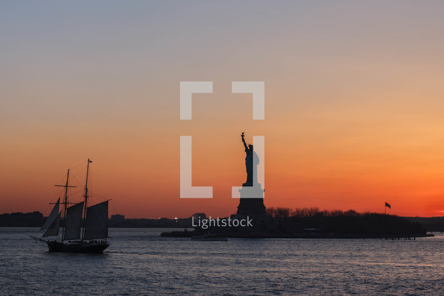 statue of liberty and ship at sunset 
